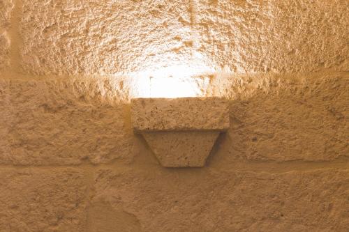 a light on the side of a stone wall at Suite Fasano in Fasano