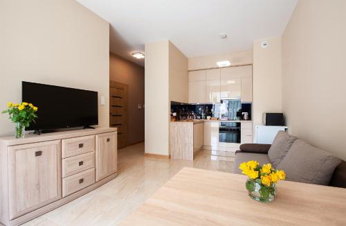 a living room with a flat screen tv on a wooden cabinet at Awangarda Home Apartment in Warsaw