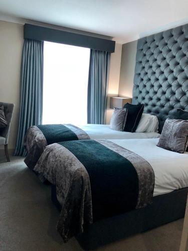 a bedroom with two beds and a large window at The Continental Hotel, Heathrow in Hounslow