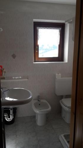 a bathroom with a sink and a toilet and a window at Rifugio "Mai Tardi" in Madesimo