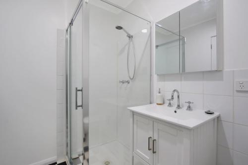 a white bathroom with a shower and a sink at Marshmallow Retreat - Bright in Bright