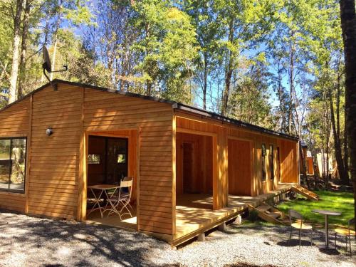 a small wooden cabin in the woods with a patio at La Escondida Pucon in Pucón