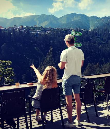 a man and a woman sitting at a table looking at the mountains at Bromo Backpacker Tosari in Pasuruan