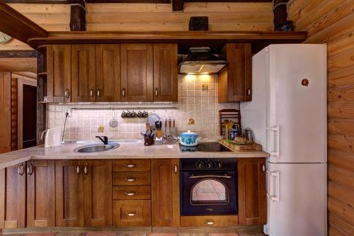 a kitchen with wooden cabinets and a white refrigerator at L - Hutir in Mykulychyn