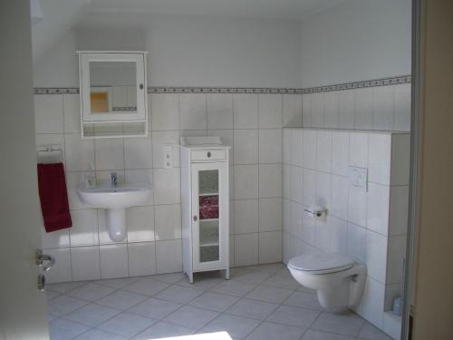 a white bathroom with a toilet and a sink at Zur Windrose Ferienwohnung an der Windmühle Labbus in Sulingen