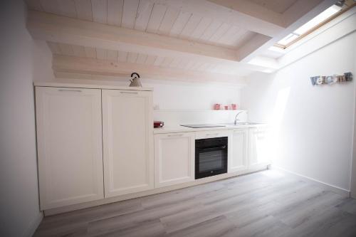 a kitchen with white cabinets and a stove top oven at Sciabika Home - Edificio Eolie in Castellammare del Golfo
