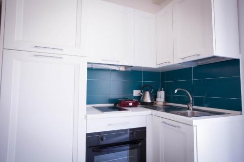 a kitchen with white cabinets and a sink at Sciabika Home - Edificio Eolie in Castellammare del Golfo