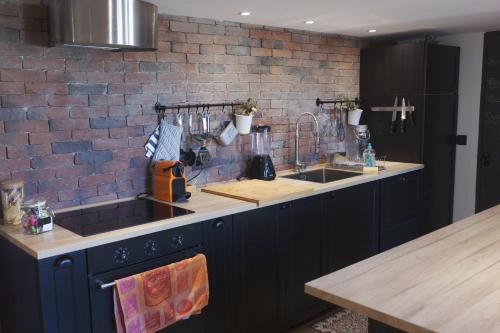 une cuisine avec des placards bleus et un mur en briques dans l'établissement La Suite Albertas, à Aix-en-Provence