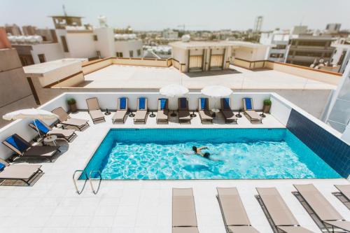 una persona nadando en una piscina en la parte superior de un edificio en Frangiorgio Hotel en Lárnaca