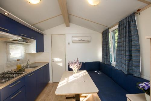 a kitchen with blue cabinets and a table with flowers on it at Mobile Homes Dvor in Manjadvorci