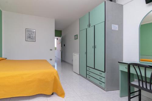 una camera con letto giallo e armadio verde di Mini Hotel a Orbetello