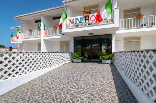 a facade of a hotel with flags on the balconies at Mini Hotel in Orbetello