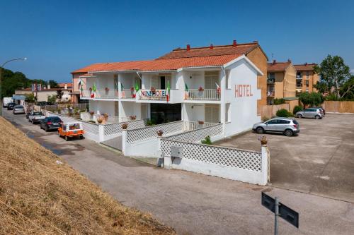 a white house with a balcony and a parking lot at Mini Hotel in Orbetello