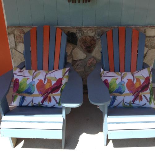 two chairs with colorful birds on them sitting on a patio at Bay Port Lodging in Frankfort