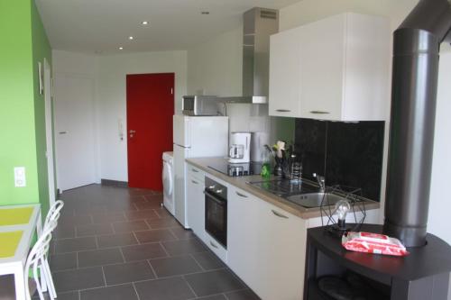 a kitchen with white cabinets and a red door at Gite du Rocher in Hazelbourg