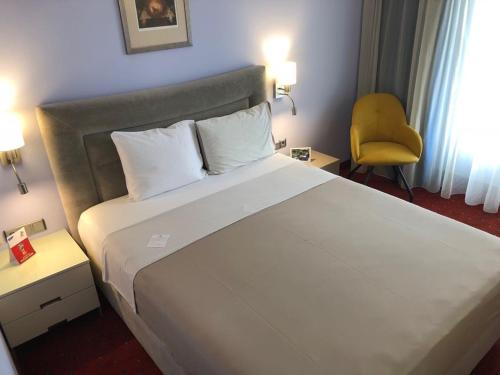 a bedroom with a large white bed with a yellow chair at Art 'Otel in Sofia
