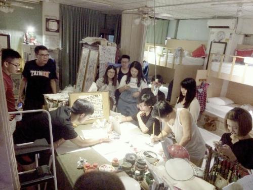 a group of people standing around a table in a room at 集集藝術家背包客之家Jiji Art Backpackers Hostel in Jiji