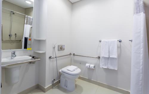 a white bathroom with a toilet and a sink at Mercure Jundiai Shopping in Jundiaí