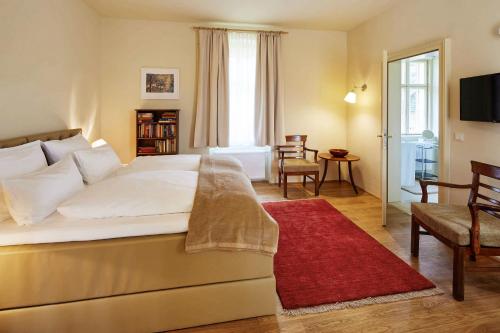 a bedroom with a large bed with a red rug at Villa Tranquillini auf Gut Guntrams in Schwarzau am Steinfelde