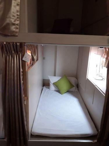a small room with a bed and a green pillow at 集集藝術家背包客之家Jiji Art Backpackers Hostel in Jiji