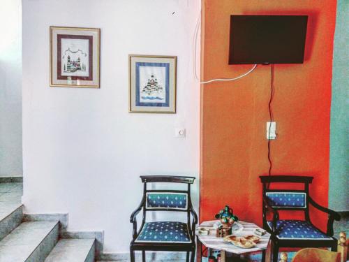 a room with two chairs and a table and a tv at Pericles Traditional Cretan Home in Stavrokhórion