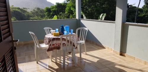 uma mesa numa varanda com uma mesa e cadeiras em Casa Mar e Montanha 1 em Trindade