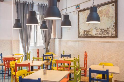 a restaurant with tables and colorful chairs and lights at LOFT Hostal in Lloret de Mar