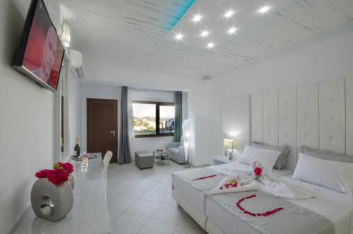 FTELIA LUXURY STUDIO ''QUATTRO'' في شاطئ ميغالي أموس: غرفة نوم بيضاء مع سرير كبير وتلفزيون