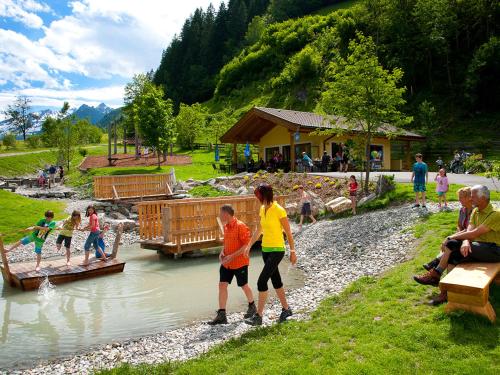 a group of people crossing a bridge over a river at Rainberghof***, Appartements in Rauris