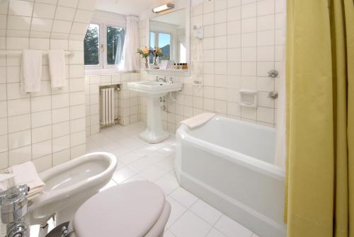 Un baño con inodoro, lavabo y bañera. en Hotel Tunquelén, en San Carlos de Bariloche