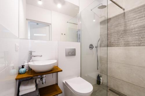 a white bathroom with a sink and a shower at Central Station Apartment - Wilcza in Warsaw