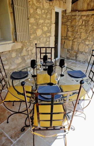 - une table en verre avec des chaises et des verres à vin dans l'établissement Au mazet de Carmélina, à Paradou