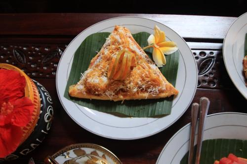 ein Stück Pizza auf einem Teller auf einem Tisch in der Unterkunft Praety Home Stay in Ubud