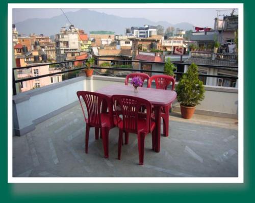 una mesa roja y sillas en un balcón con vistas en Le Rhododendron Chambres D'hotes, en Katmandú