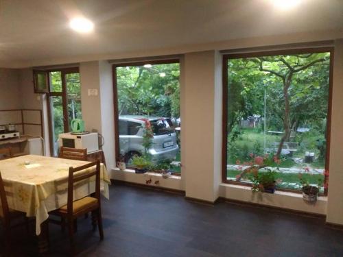 ein Esszimmer mit einem Tisch und zwei großen Fenstern in der Unterkunft Holiday Home Ekaterine in Telawi