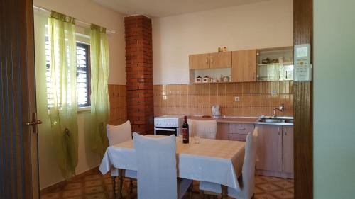 a kitchen with a table and white chairs in a room at Vacation home Ivan in Kašić