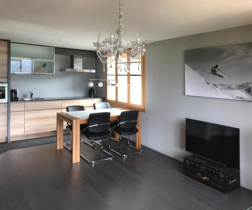 a living room with a dining room table and a television at Alp n' rose in Hasliberg