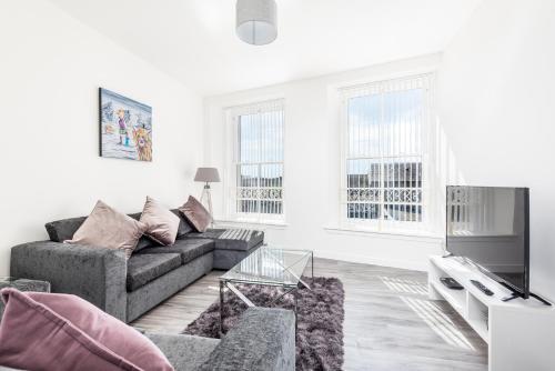 a living room with a couch and a tv at Casa Fresa - Cowgate Apartment in Dundee