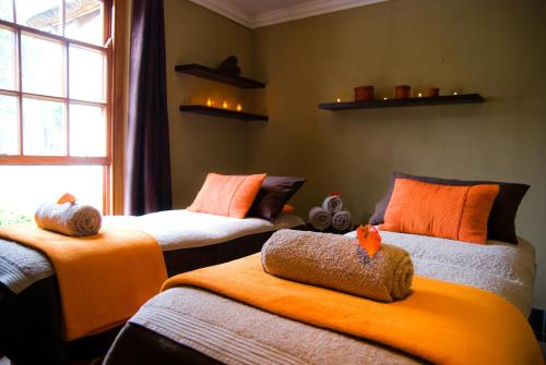 a room with two beds with orange sheets and a window at Kievits Kroon Gauteng Wine Estate in Pretoria