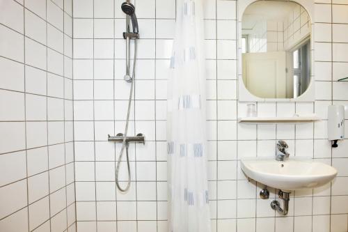 a white tiled bathroom with a shower and a sink at Hotel Nora Copenhagen in Copenhagen