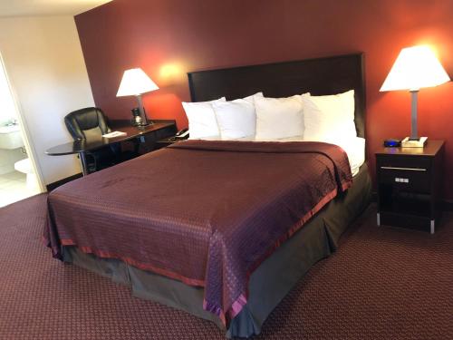 Franklin ParkにあるRegal Inn Chicago O'Hare - Franklin Parkの大きなベッドと椅子が備わるホテルルームです。