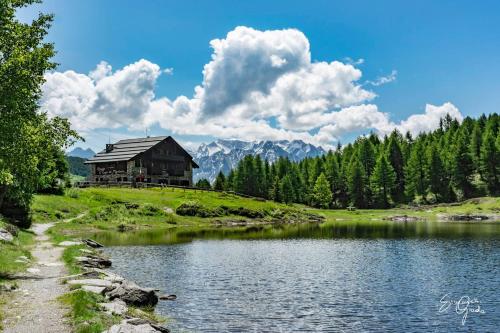 a house on a hill next to a lake at RIFUGIO AL LAGO DEL MORTIROLO in inverno raggiungibile solo a piedi in Monno