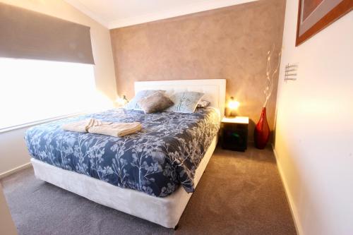 a bedroom with a bed with a blue and white comforter at Full Circle Apartments in Jindabyne