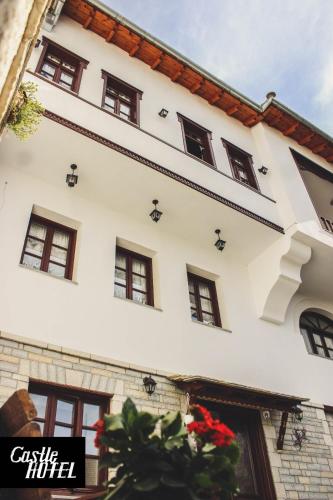 a white building with windows and flowers in front of it at Castle Hotel in Gjirokastër