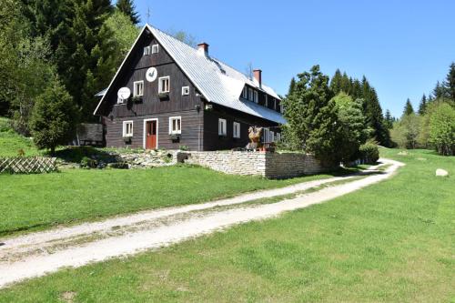 a black house on a hill with a dirt road at Horská bouda U Kokrháče in Dolní Malá Úpa