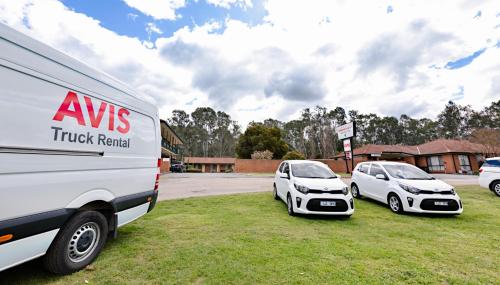 two white cars parked in a field next to a truck at Advance Motel in Wangaratta