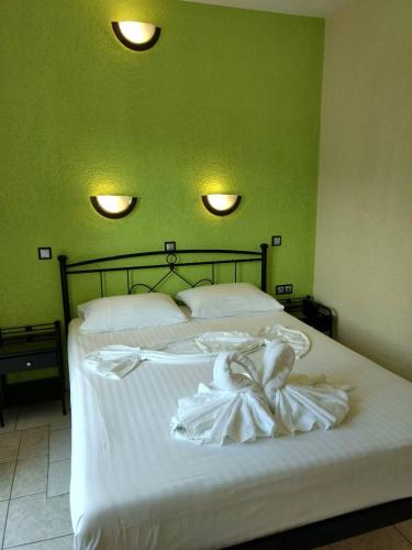 a bedroom with a bed with white sheets and two lights at Evelin hotel in Pythagoreio