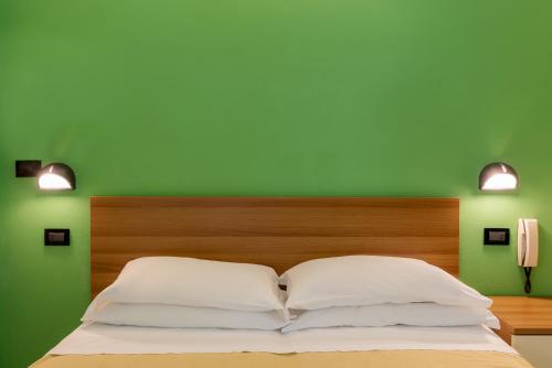 a green bedroom with a bed with two white pillows at Hotel T Depandance in Rimini