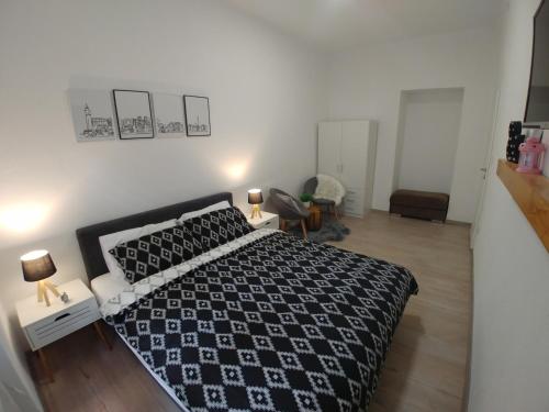 Schlafzimmer mit einem Bett mit einer schwarzen und weißen Bettdecke in der Unterkunft Apartments Sari in Sarajevo