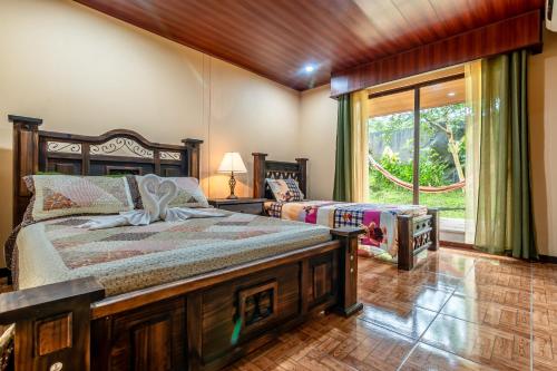 a bedroom with two beds and a large window at Aunty Arenal Lodge in Fortuna